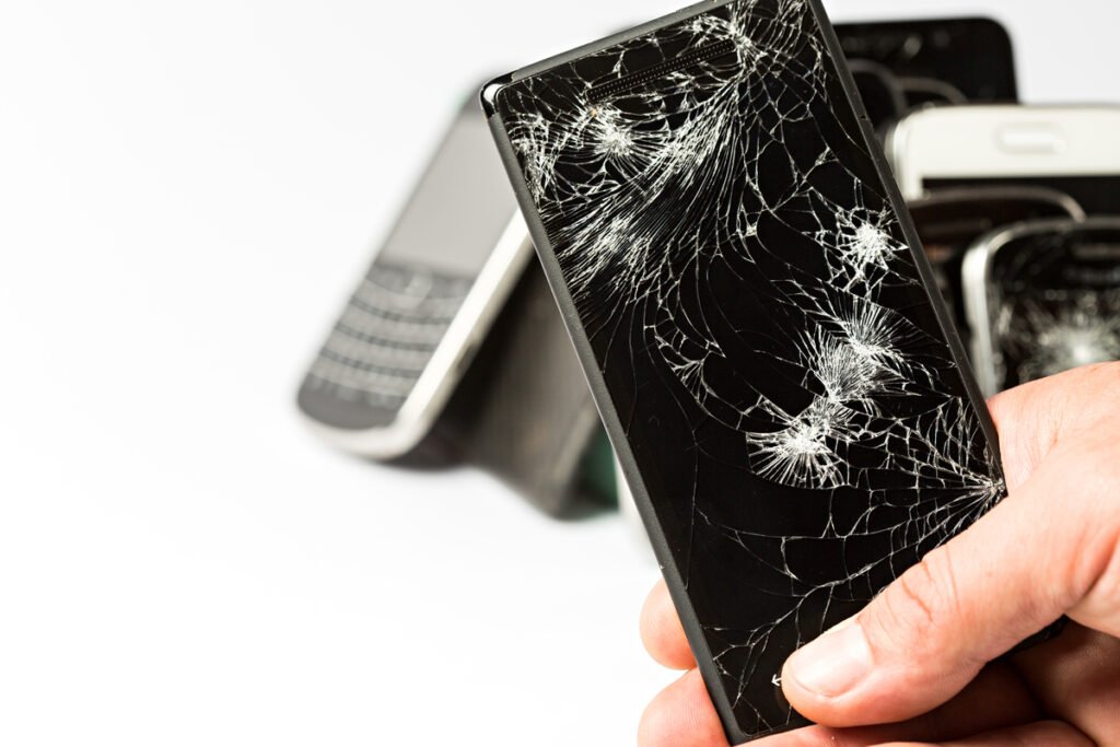 Broken smartphones with damaged display screens on a variety of smartphones.